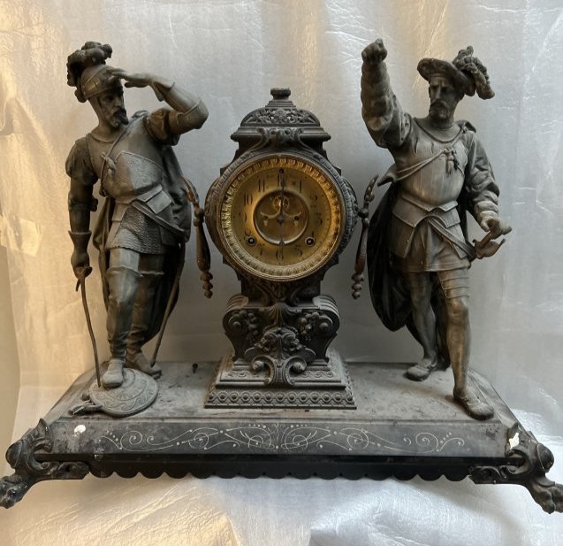 AN AMERICAN LATE 19TH CENTURY SPELTER AND CAST IRON FIGURAL MANTLE CLOCK ANSONIA CLOCK CO. NY: AN AMERICAN LATE 19TH CENTURY SPELTER AND CAST IRON FIGURAL MANTLE CLOCK ANSONIA CLOCK CO. NY , FLANKEKED BY A PAIR MUSCATEERS ON A PLATEAU BASE WITH RAISED LIONS PAW FEET , VERY HEAVY STANDS 20" 24" 