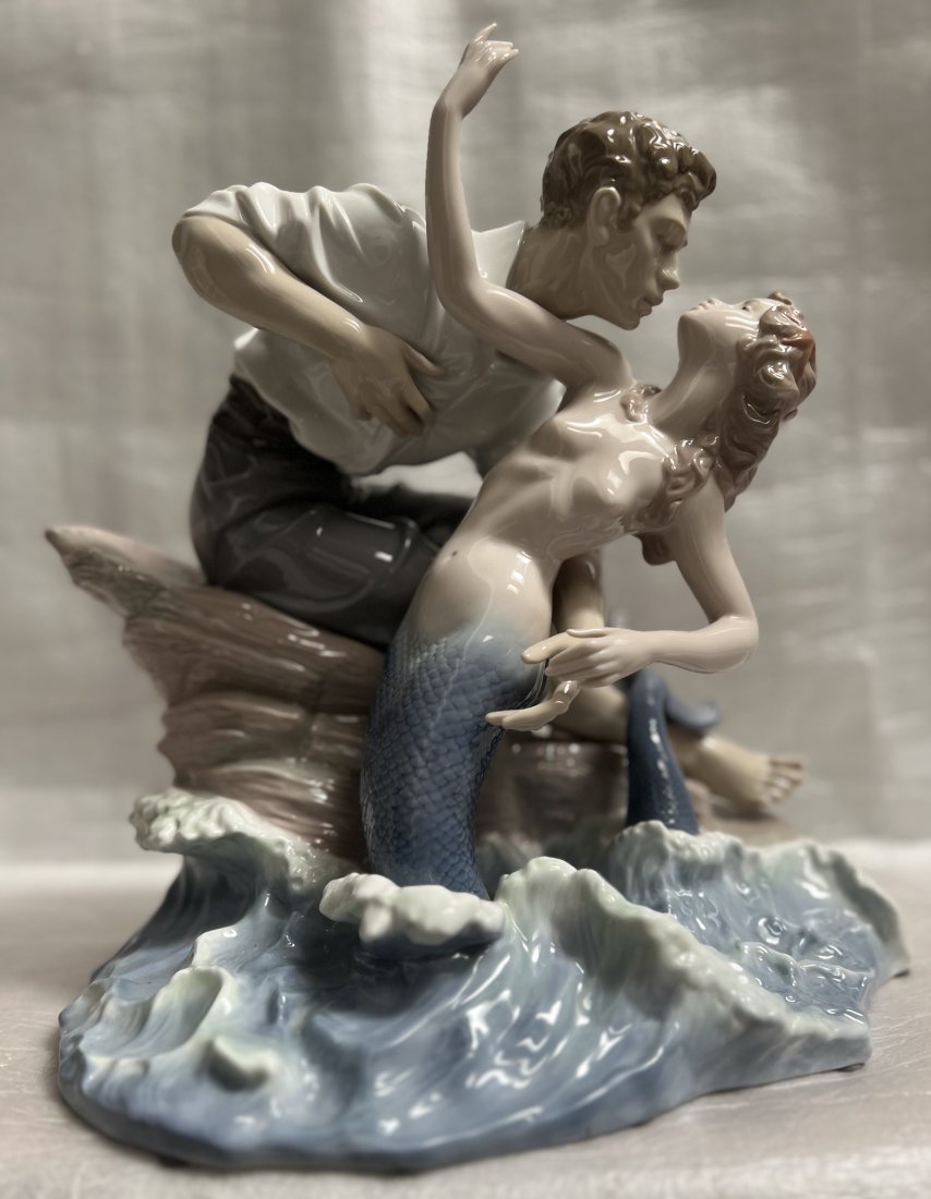 LLADRO PORCELAIN FIGURINE "SEA OF LOVE" #6432 13"T 13"W 10" D: This beautiful porcelain figurine from Lladró features a stunning depiction of a man and a mermaid embracing in a scene titled "Sea of Love". The figurine measures 13 inches in height, 13 inches in w