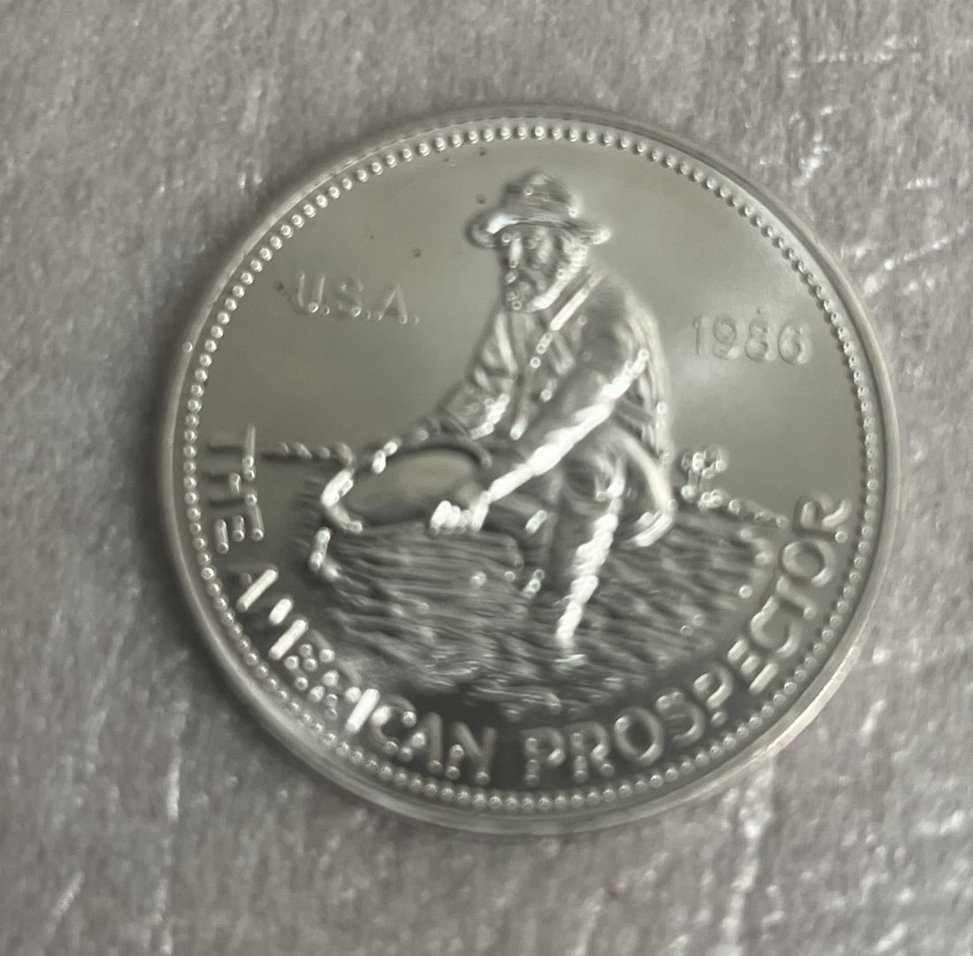 Engelharh one troy ounce 999 fine silver "The American Prospector" 1986 MS 65: This Engelharh one troy ounce 999 fine silver coin, titled "The American Prospector," was minted in the United States in 1986. It has been graded MS 65 and contains 1 oz of precious metal. The coin fe