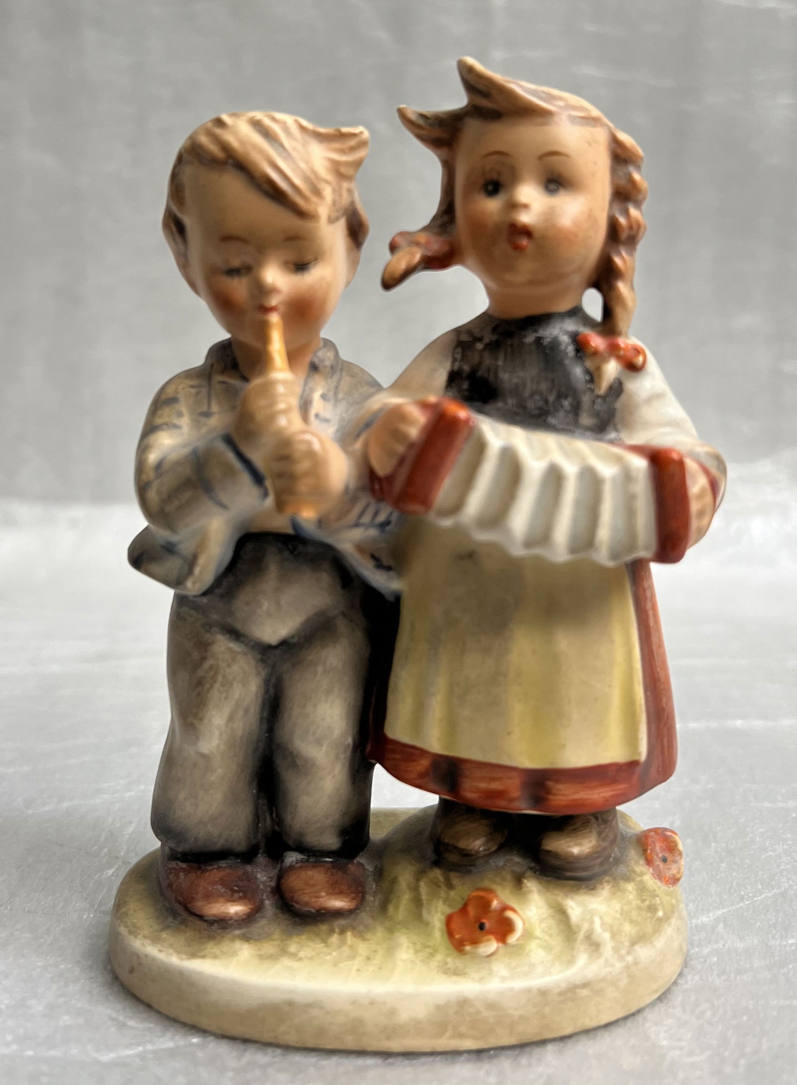 Hummel Figurine "Birthday Seranade" Hum 218/210: The "Birthday Seranade" Hummel figurine (Humm 218/210) is a small collectible piece featuring an all-over pattern in multicolor. Manufactured in Germany during the 1950s by Hummel and Goebel, this fig