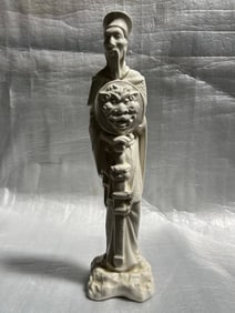 White porcelain figure, likely of Chinese origin, depicting a warrior or a significant figure holdi