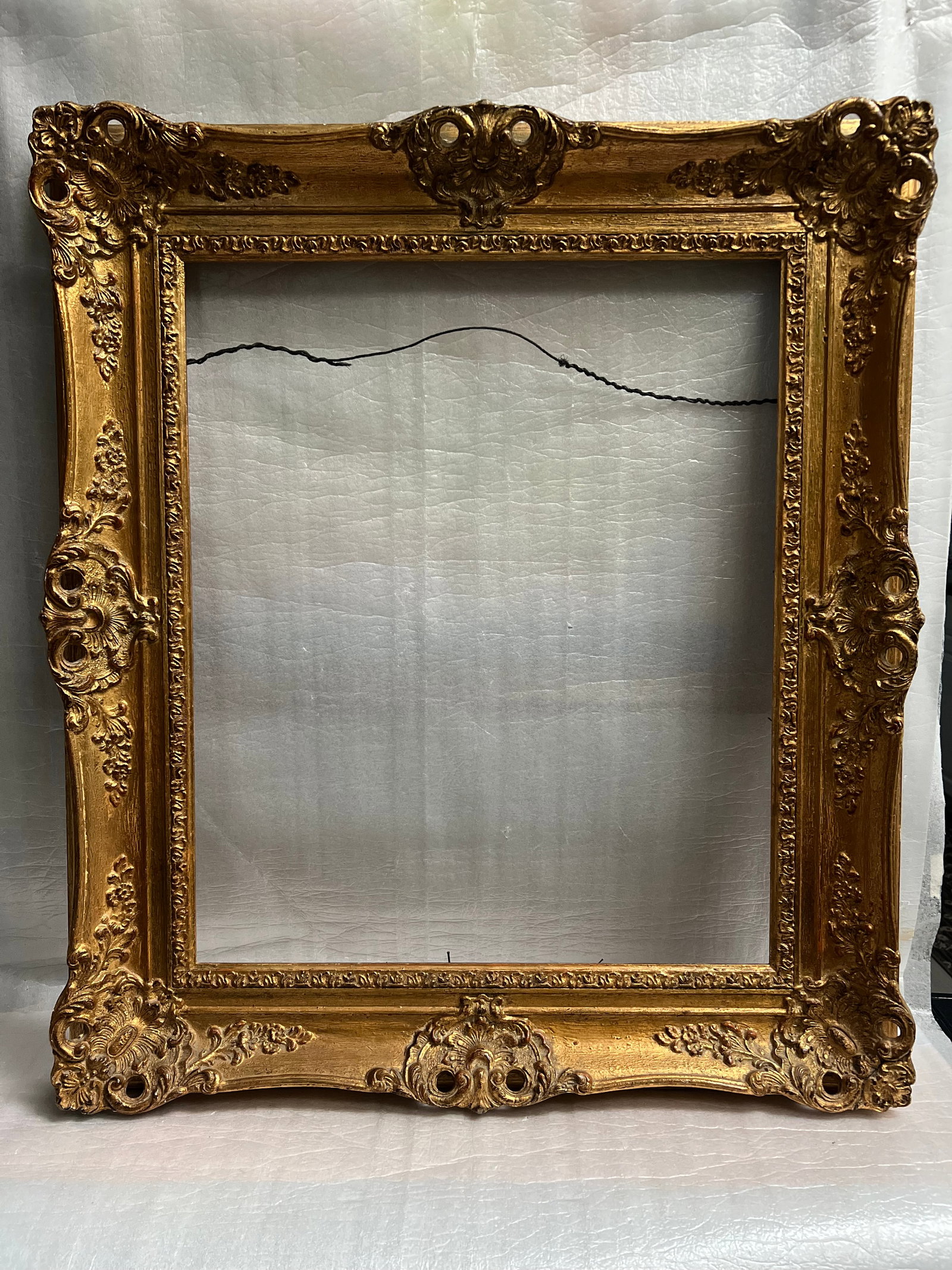 Mid 19th C European Gold Leaf Frame in the Rococo Style with Crest: Antique Gold Rococo Style Frame, characterized by its ornate, asymmetrical, and curvilinear details, including scrolls, shells, and floral motifs, often highlighted with gilding. This style emerged in
