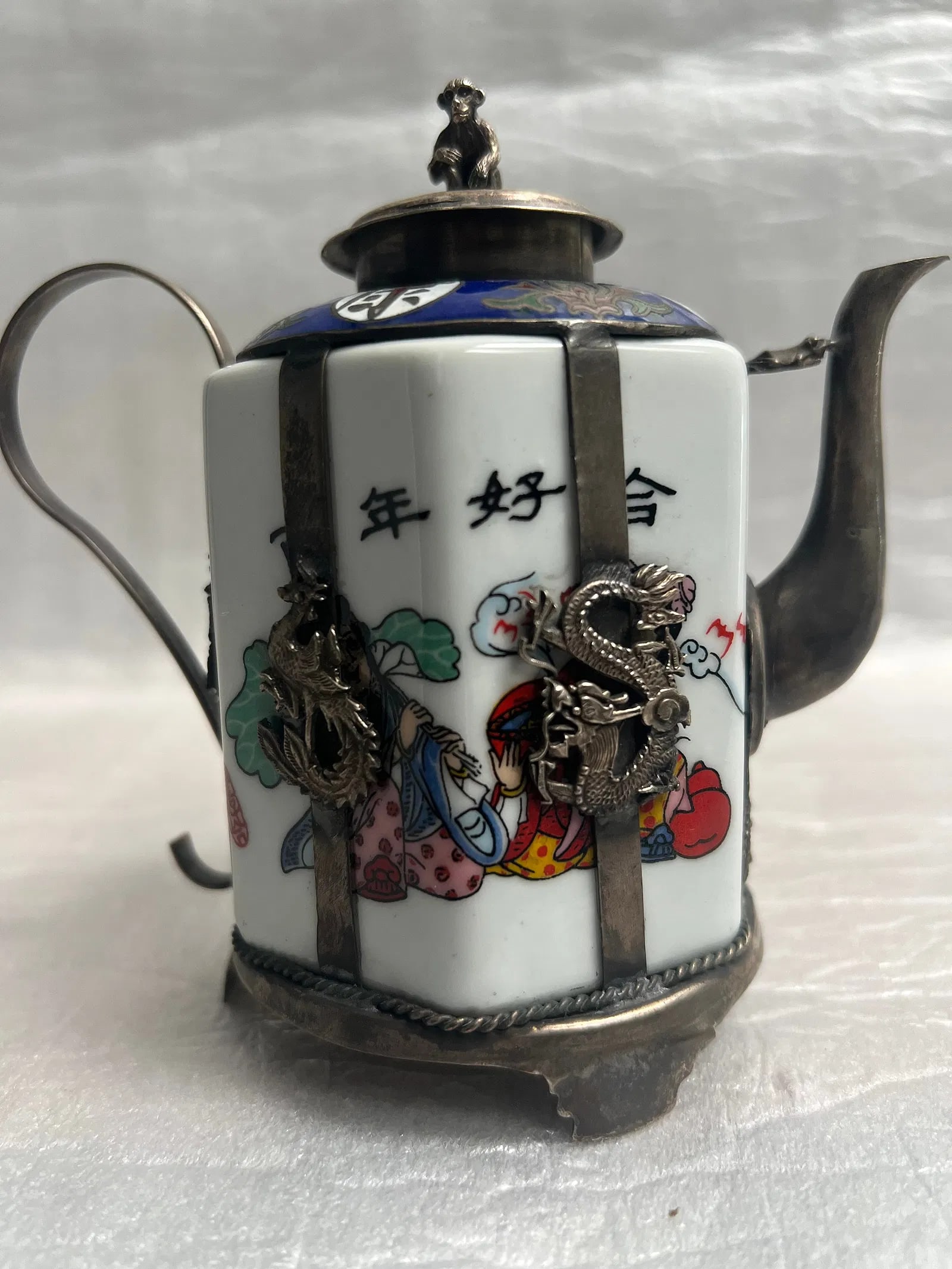 Chinese Miniature Porcelain Teapot with Silver overlay: This is a Chinese miniature porcelain teapot with silver overlay, likely from the early 20th century. Key features:Material: It features a porcelain body with intricate silver overlay. Design: The por