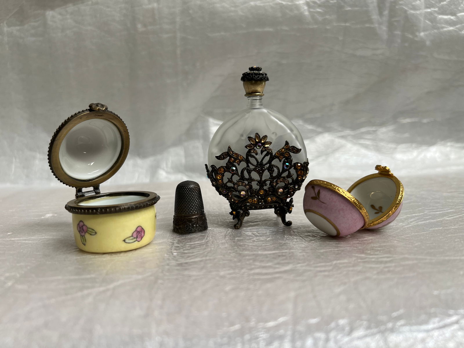 A Collection of Vintage Decorative Items: collection of vintage-inspired decorative items, likely a set of a perfume bottle, two trinket boxes, and a thimble. These items are often sold as collectibles or vanity decor. The central item is a f