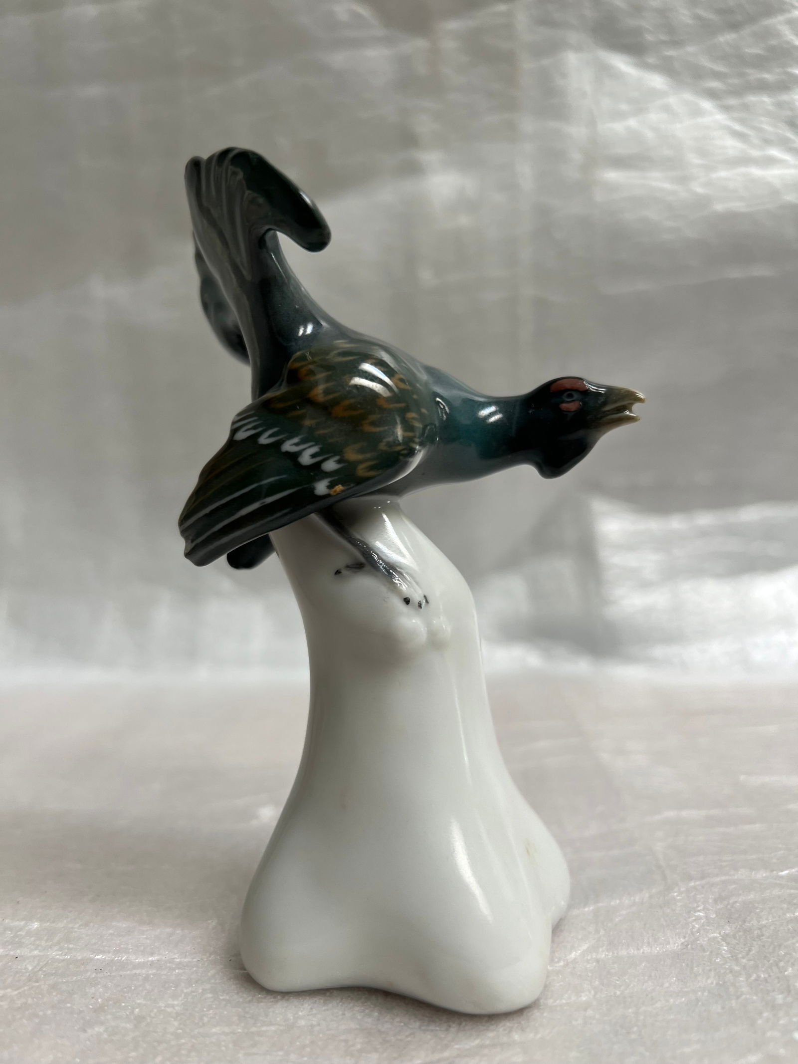 Goebel Porcelian Figurine "Bird in Flight": The image displays a Goebel porcelain figurine of a bird in flight, likely a grouse or capercaillie. Goebel, a German company founded in 1871, is known for its fine porcelain and decorative items. The