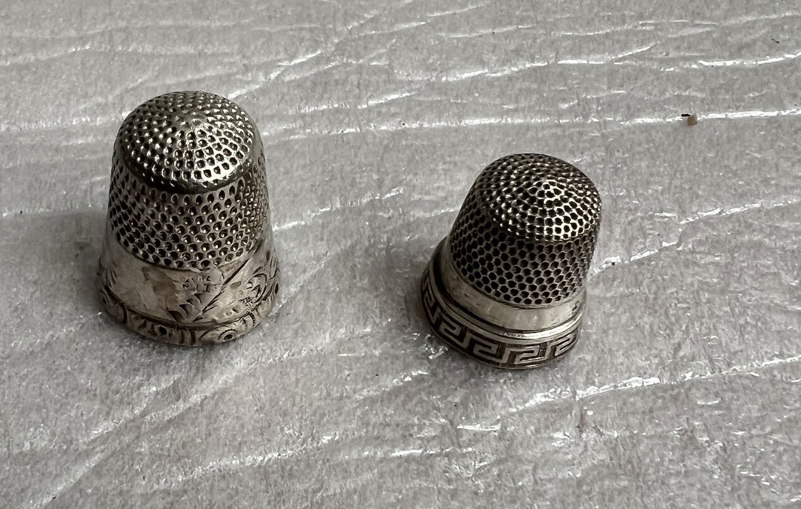 vintage or antique sterling silver thimbles: The items pictured are vintage or antique sterling silver thimbles, used as protective covers for the finger during sewing. Material and Design: The thimbles are made of sterling silver and feature te
