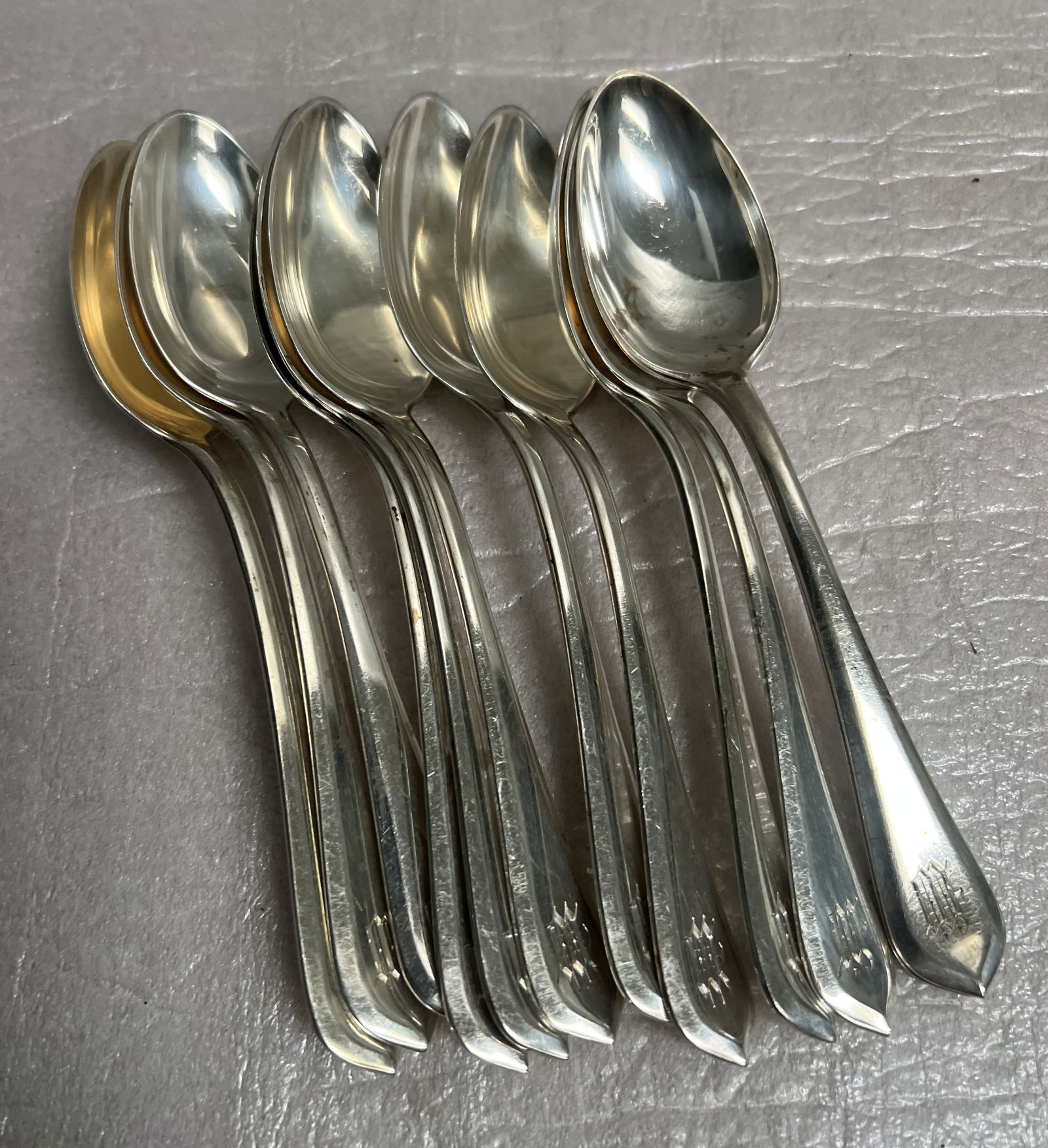 Christofle set of 12 Sterling Silver Spoons 10.9 oz: The image shows a set of 12 silver spoons, likely a set of bouillon or soup spoons, possibly in the "Spatours" pattern by Christofle based on the visible hallmarks. Here is some general information ab