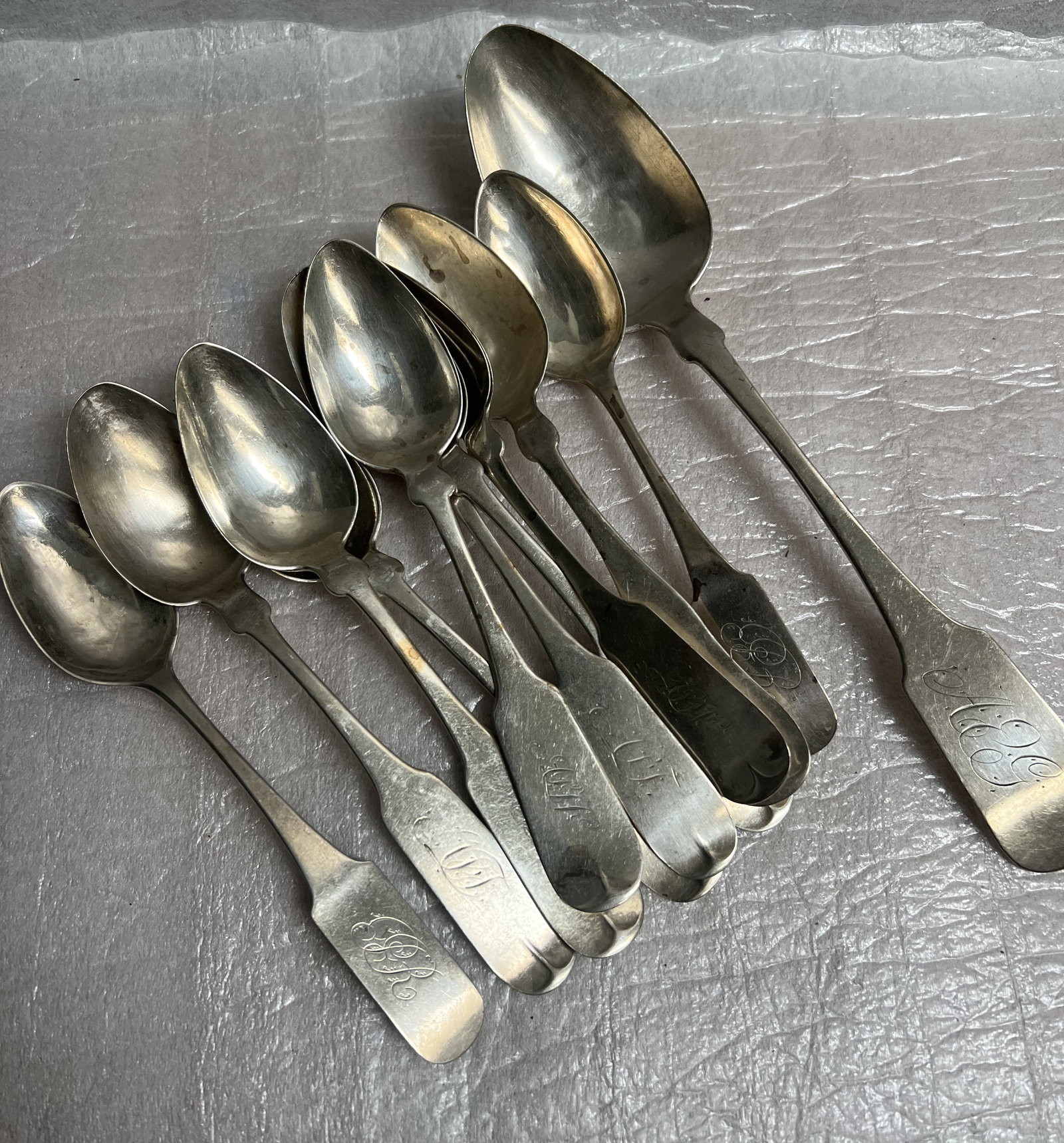 Set of 11 Antique Spoons Which Appear to be Coin Silver c 1800s 8.2 Oz: The image displays a collection of antique spoons, which appear to be coin silver rather than sterling silver, based on similar examples found in search results. Key characteristics include:Material: 