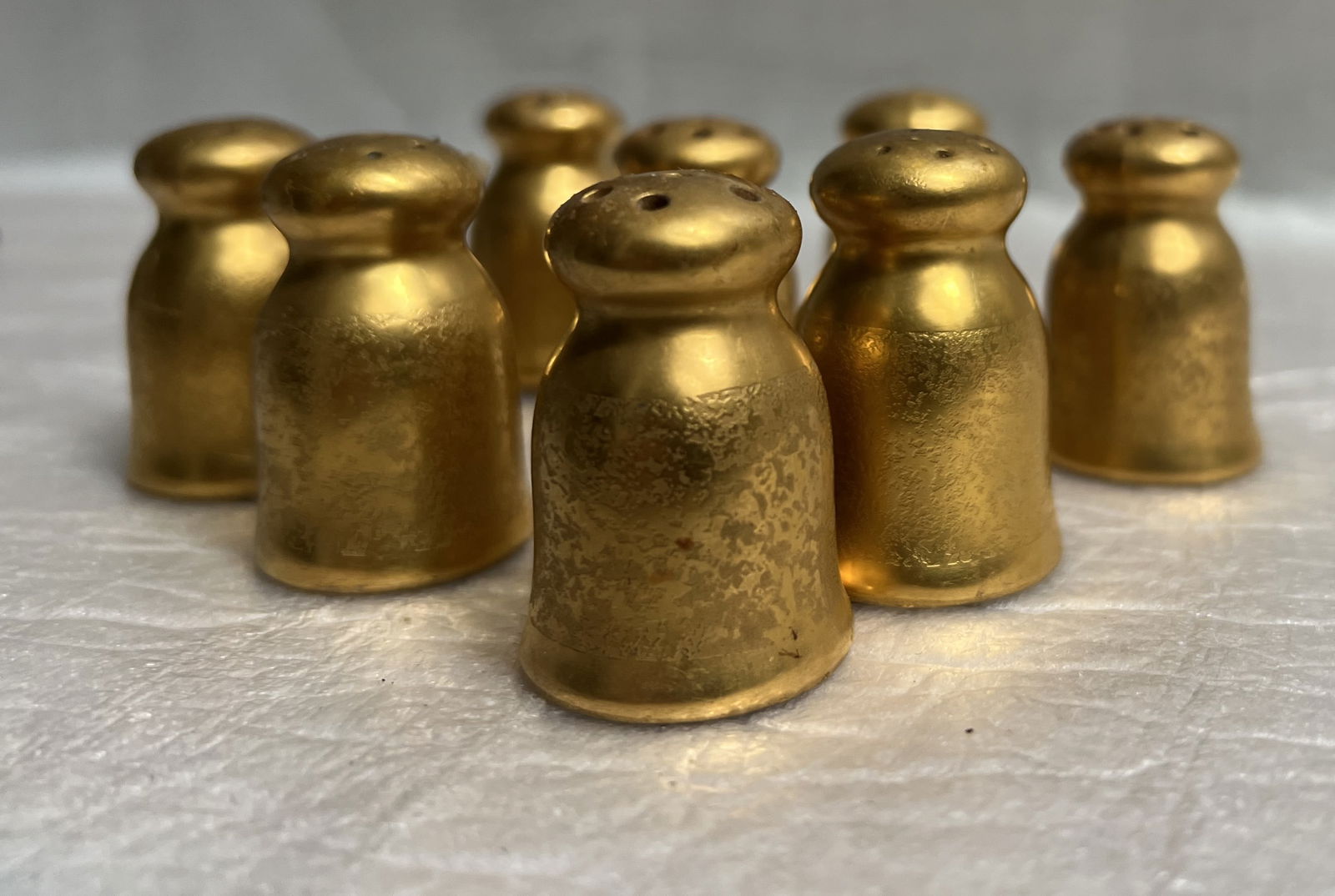 Set of 8 Vintage Gilded Porcelain Miniature Salt and Pepper Shakers: The image displays eight gold-gilded salt and pepper shakers, likely vintage Pickard items. Material and Finish: The shakers are made of porcelain or ceramic and feature a gold-encrusted or gilded fin