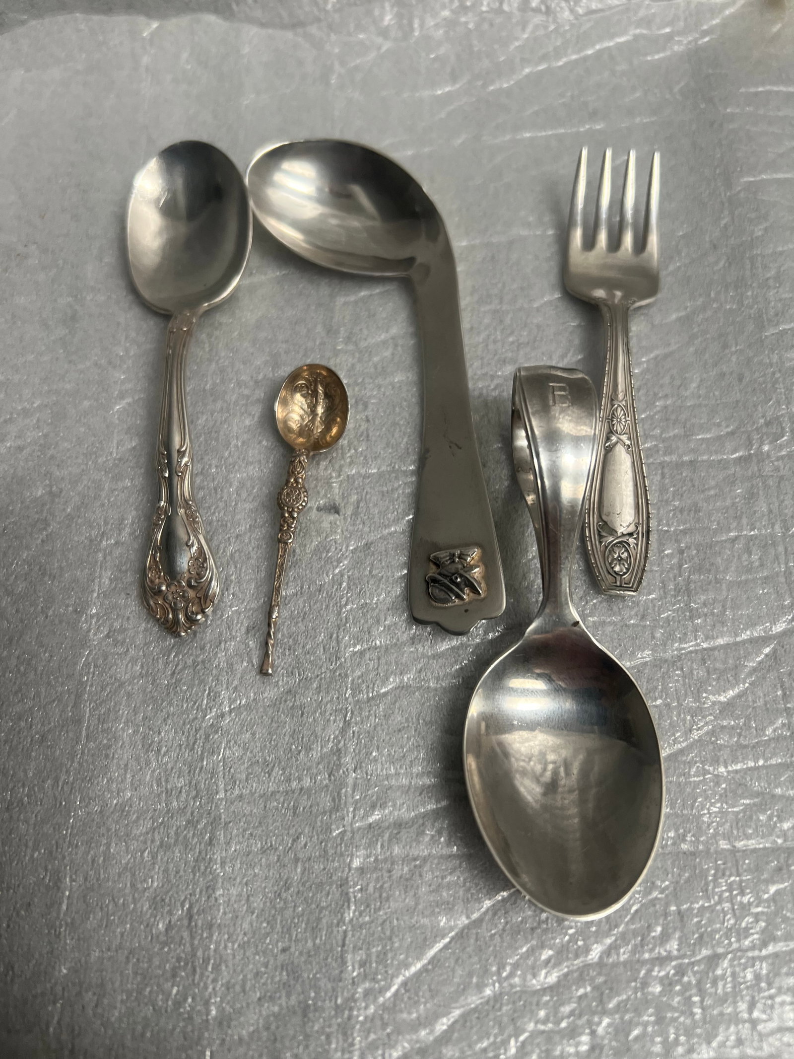 A collection of miscellaneous sterling silver flatware pieces: a collection of miscellaneous sterling silver flatware pieces, likely from an auction or estate sale. The assortment includes various items: One large serving spoon with a bent handle. One medium-size