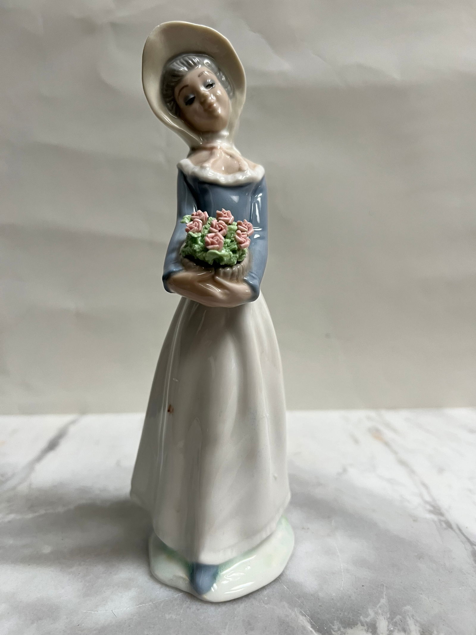 Vintage Tengra Valencia Spain Porcelain Figurine - Girl with Bonnet and Flower Basket - 9": This statue is a handmade porcelain figurine from Tengra, a Spanish company based in Valencia that was active primarily between the 1960s and 1990s. Known for their "Lladro-style" aesthetic, these pie