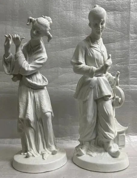 PAIR OF CHINESE FIGURINRS MAN WHO IS A BIRD TRADER BOTH# 23/469 &FEMALE MERCHANT: This pair of Chinese figurines features a man who appears to be a bird trader and a female merchant. The intricate details of their clothing and accessories showcase the skilled craftsmanship of the a