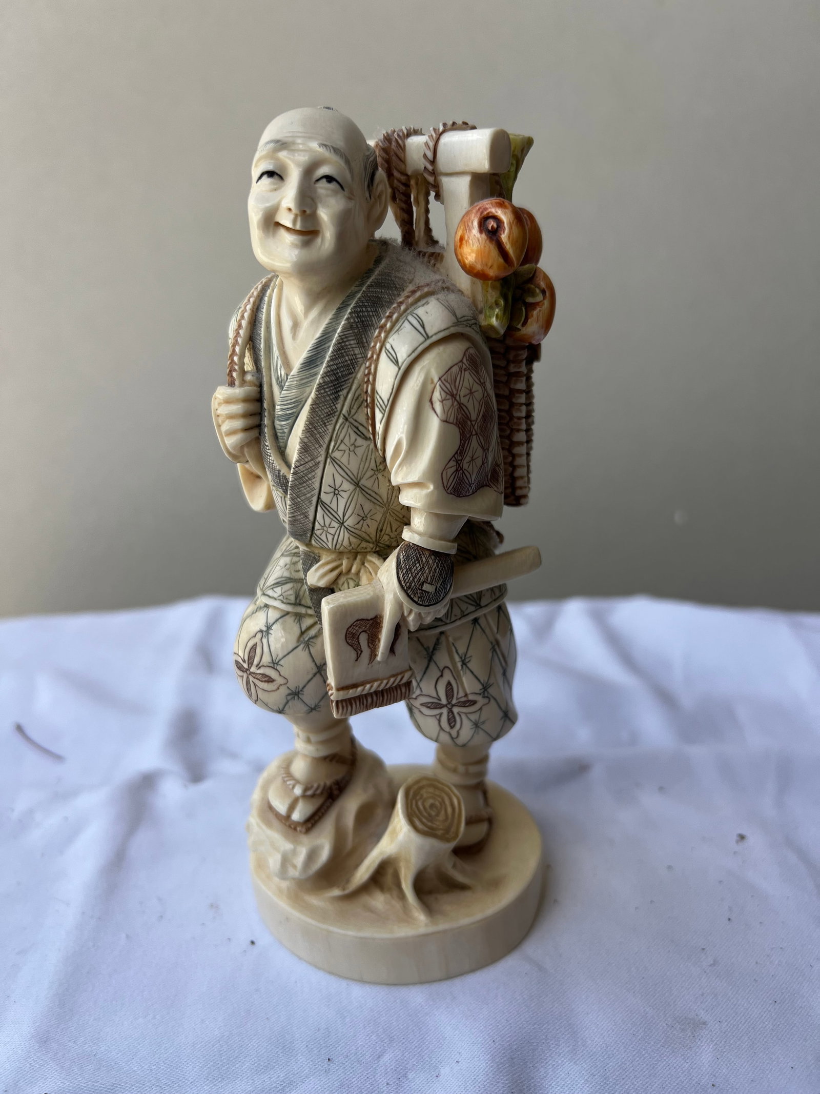 Japanese Meiji/Taisho Style Carved Bone Figurine of a Traveling Fruit Vendor: Material & Construction: This is a finely detailed Japanese-style figural carving of a traveling peasant, farmer, or vendor, masterfully constructed from natural bone. It displays the intricate multi-