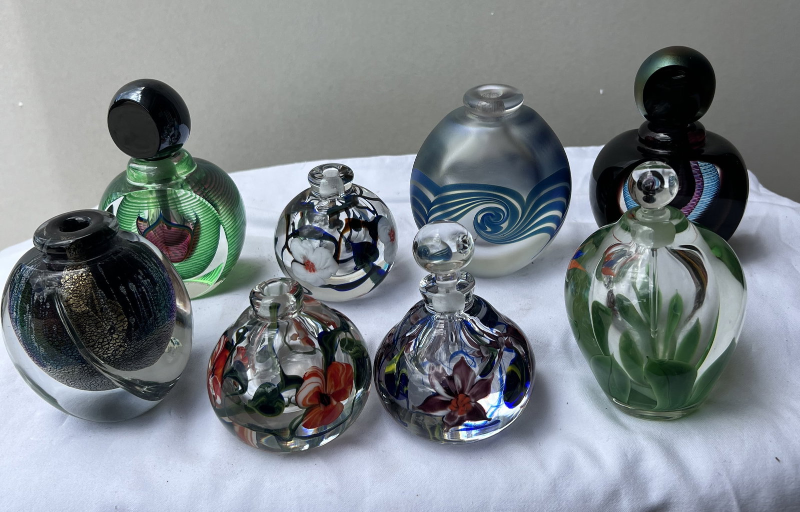 Lot of 8 Vintage Studio Art Glass Perfume Bottles, Incl. Signed Correia 1989: Itemized Breakdown & Identifications1. The Correia "Poppy" Internal Millefiori / Lampwork Bottles (Front Row, Center) Description: As shown in detail in image_2.png, the bottom of the front-center-lef