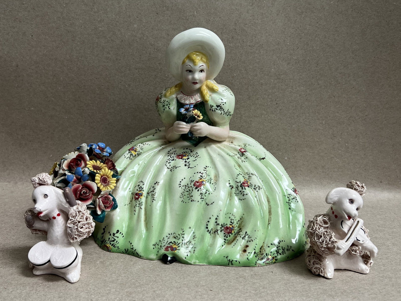 This 3-piece vintage ceramic figurine set features a seated lady paired with two musical spaghetti p: This 3-piece vintage ceramic figurine set features a seated lady paired with two musical spaghetti poodles. Seated Lady Figurine: Measures 7" H x 9" W. Crafted in a Southern Belle / Victorian style, s