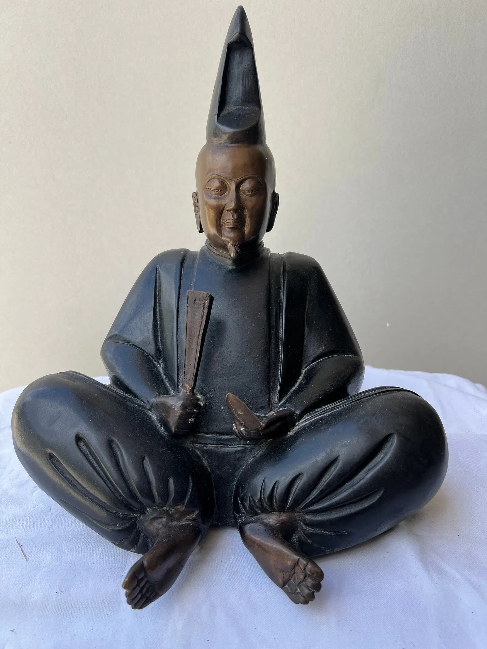 Japanese Meiji/Taisho Period Patinated Bronze Seated Court Noble (Kuge) or Deity: The statue depicts a dignified, bearded male figure seated cross-legged in a relaxed yet formal posture. Attire & Iconography: He is dressed in traditional, voluminous court robes (sokutai), character