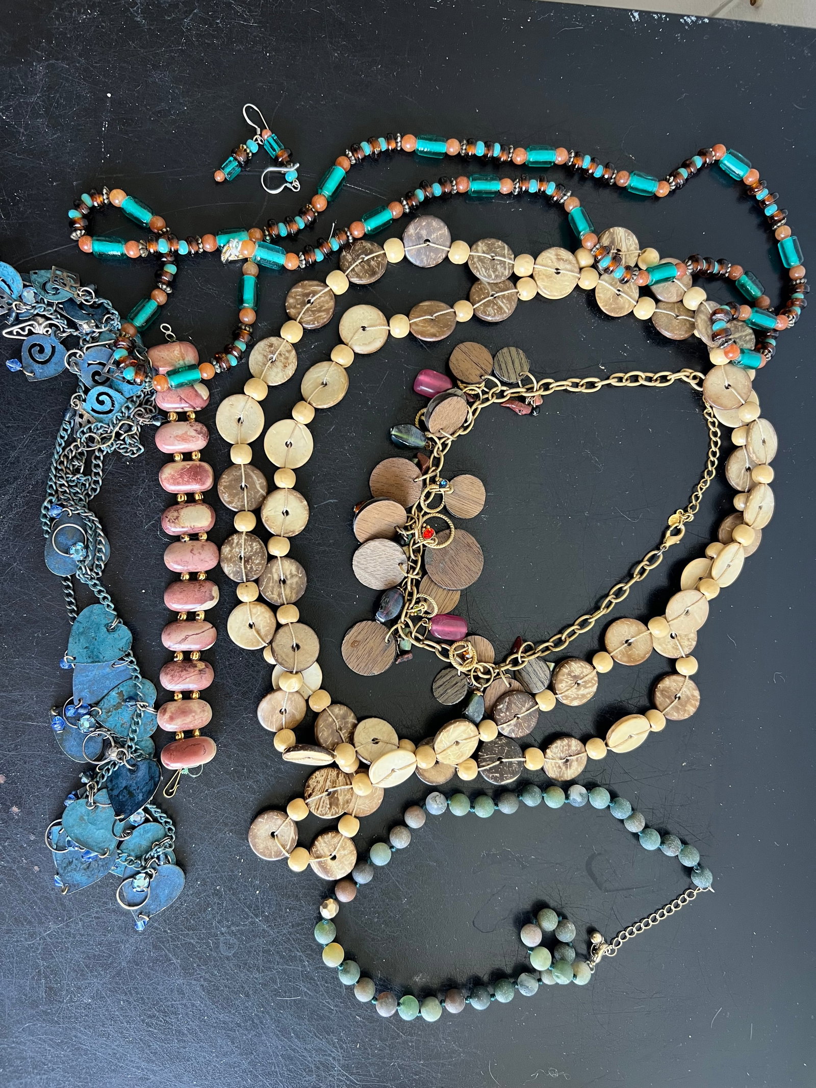 An eclectic collection of bohemian and artisan-style jewelry featuring organic materials, earth tone: An eclectic collection of bohemian and artisan-style jewelry featuring organic materials, earth tones, and vibrant accents. Turquoise Glass Tube Strand: Long strand constructed with vibrant turquoise 