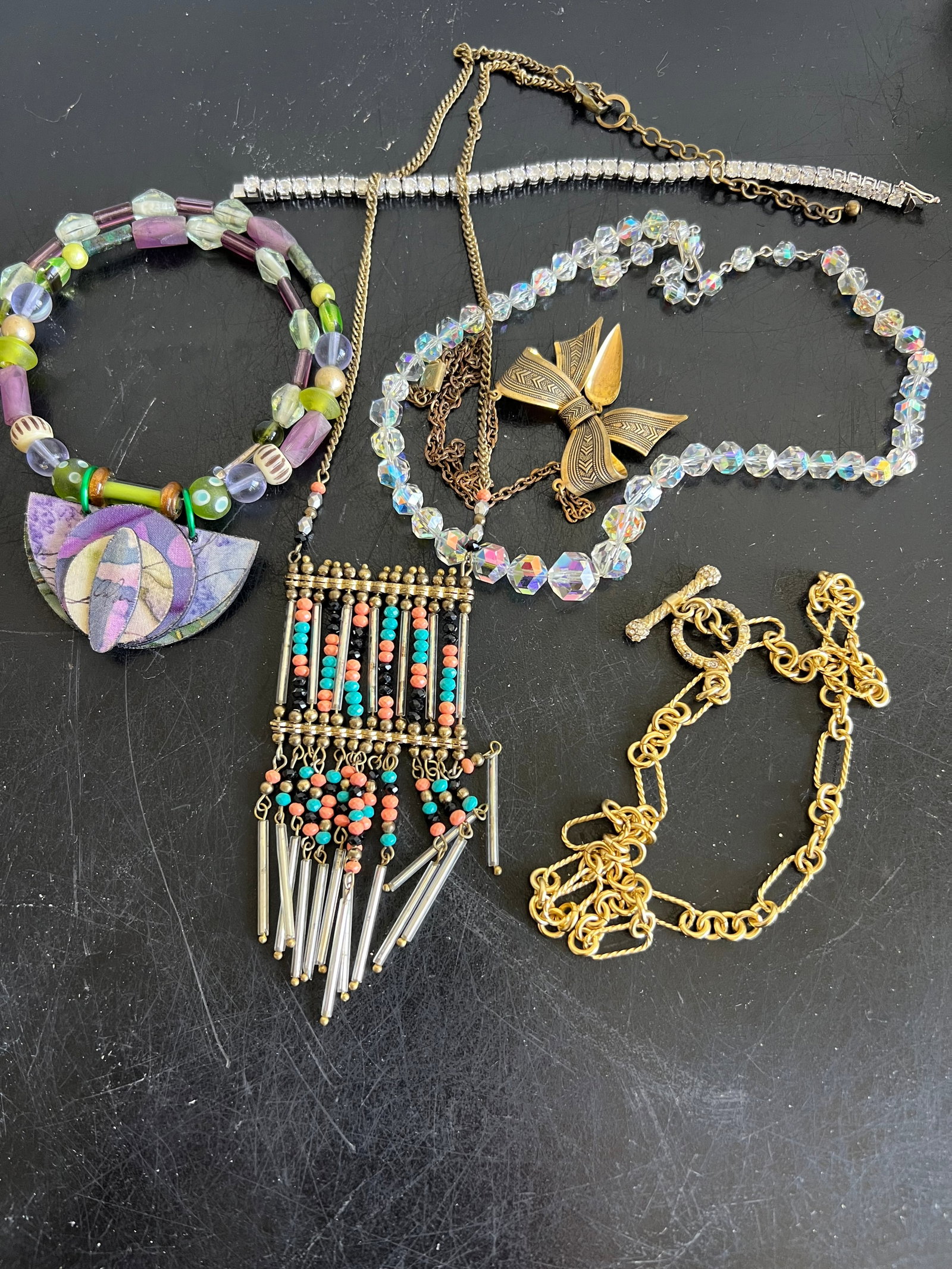 Eclectic Vintage & Statement Jewelry Collection: Artisan Beaded Collar Collar: Features a mix of purple, green, and iridescent beads with a layered geometric paper-craft pendant. Beaded Fringe Pendant Necklace: An antique brass-toned chain supportin