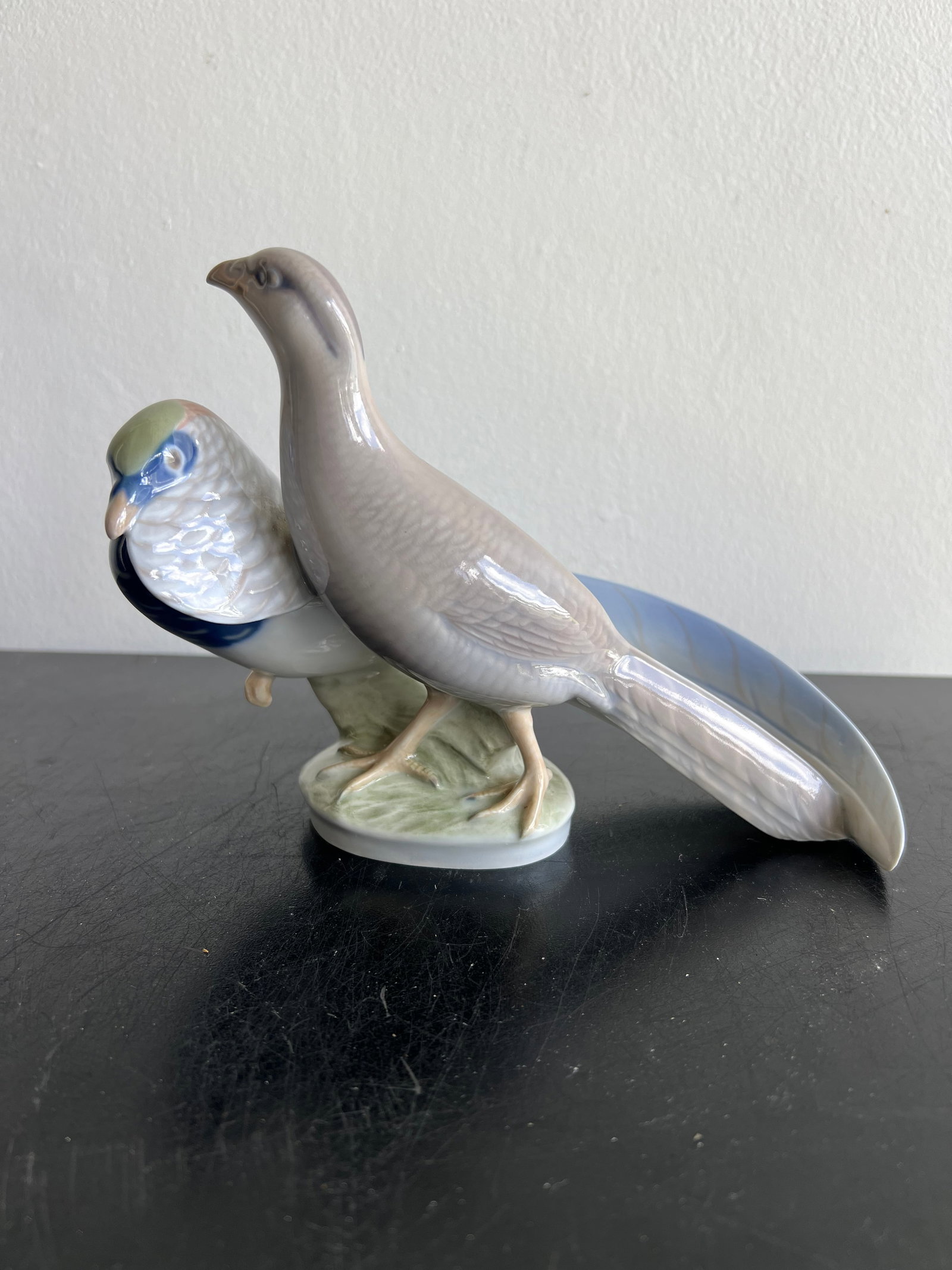 Royal Copenhagen Porcelain "Pair of Pheasants" Figurine (#862): Royal Copenhagen Porcelain "Pair of Pheasants" Figurine (#862)DescriptionCrafted in Denmark from fine porcelain, this piece features a pair of pheasants modeled in a naturalistic pose atop a subtle gr