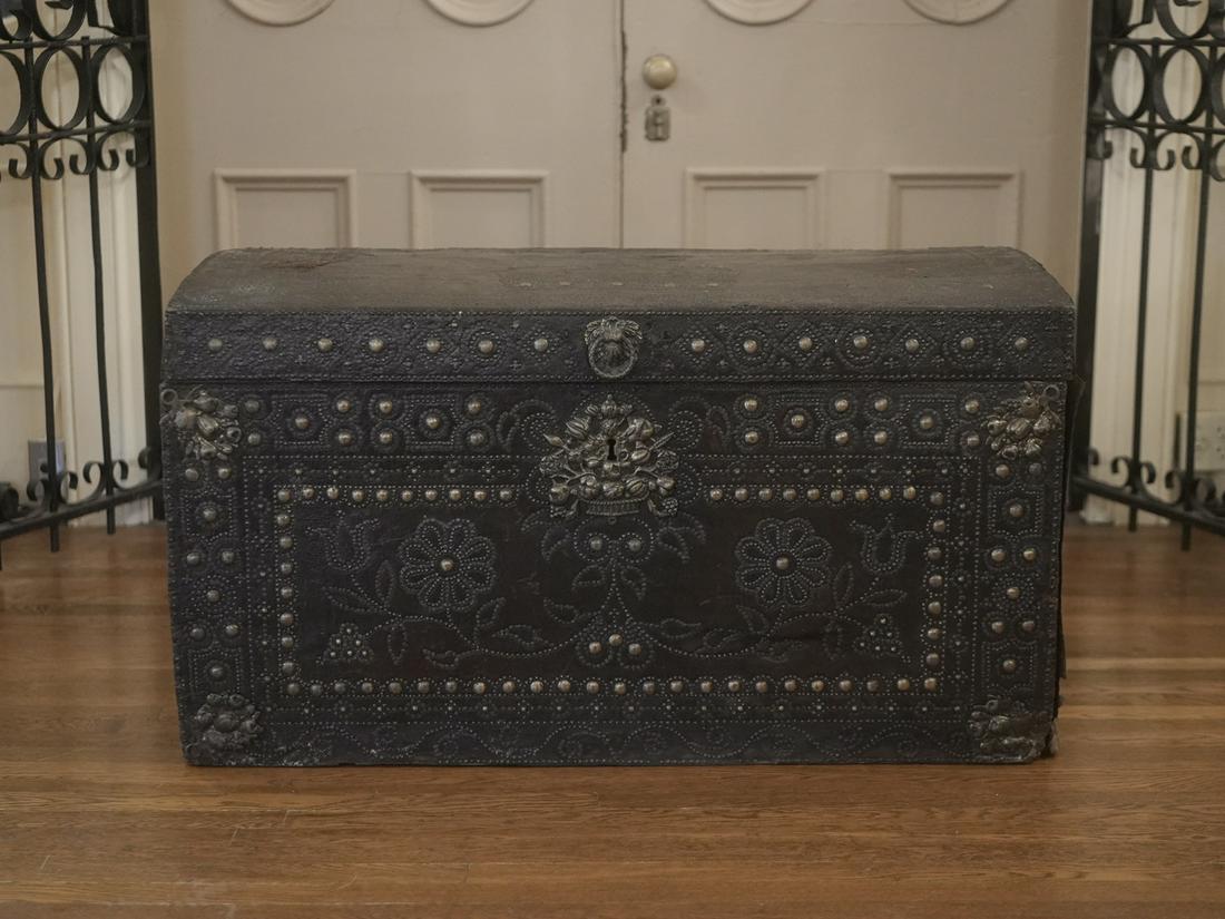Antique Leather Covered Trunk: Antique leather Trunk with brass designs. The top has a crown and a date of 1638. The interior is lined with English newspapers dated 1841. The sides feature wrought iron carrying handles.