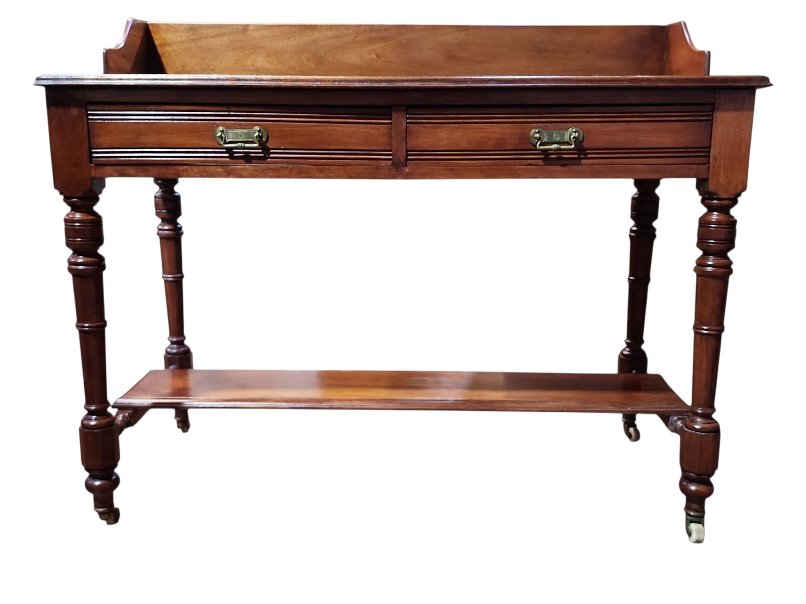 English Victorian Mahogany Side Table With Gallery: Stunning late 1800s English Victorian mahigany side table with gallery back, in excellent condition. Double drawers with brass pulls over fixed lower shelf, on original castors, suitable as hall conso