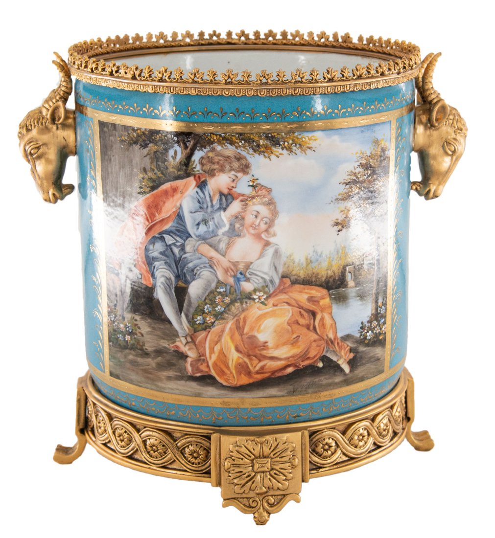 Bronze and Porcelain Wine Chiller: Up for auction is a highly detailed hand painted wine chiller. This piece is highlighted by the intricate bronze work at its base and on its handles. It depicts a classical Rococo scene on each side, 