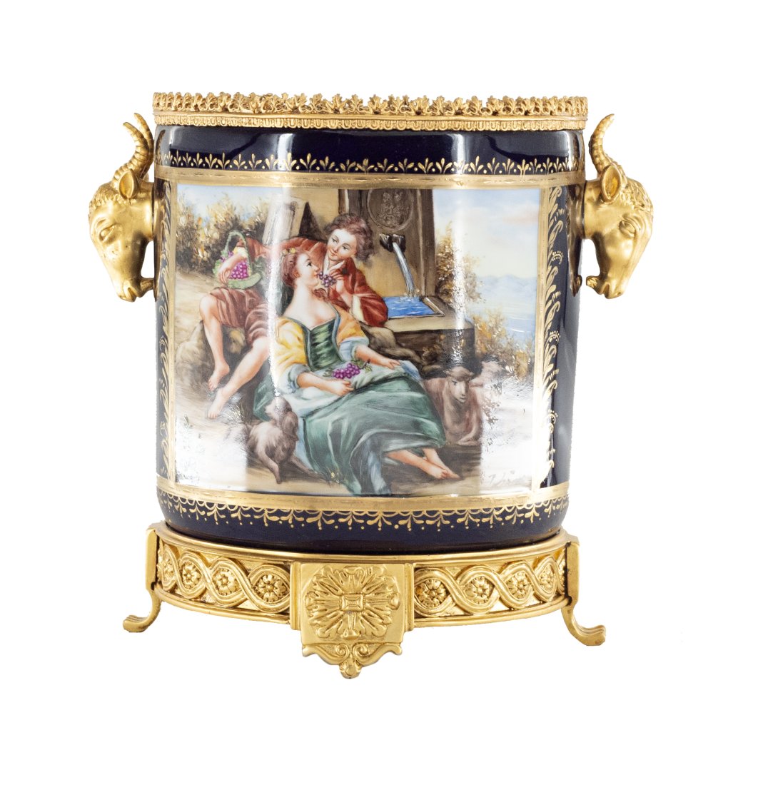 Bronze and Porcelain Wine Chiller: Up for auction is a highly detailed hand painted wine chiller. This piece is highlighted by the intricate bronze work at its base and on its handles. It depicts a classical Rococo scene on each side, 