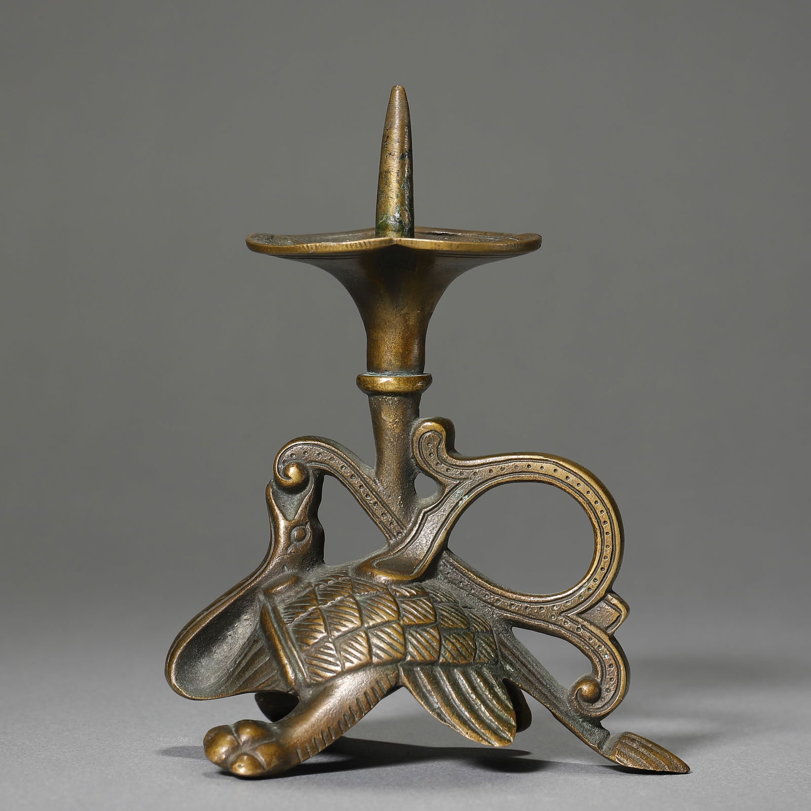 A CHINESE BRONZE CANDLESTICK WITH XUANWU MOTIFS.: A CHINESE BRONZE CANDLESTICK WITH XUANWU MOTIFS. Dimensions: Height: 4 3/4 in. (12 cm) ALL ITEMS SOLD AS IS, NO RETURNS Condition: Any statement made in any catalogue or otherwise regarding the or