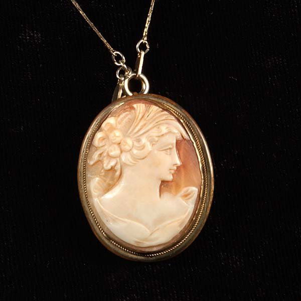 Cameo brooch, vintage carved shell: Cameo brooch, vintage carved shell with right-facing figure of a lady with three roses in her upswept hair. Cameo is set in an oval frame with beaded surround and is attached to a tangle-free chain.