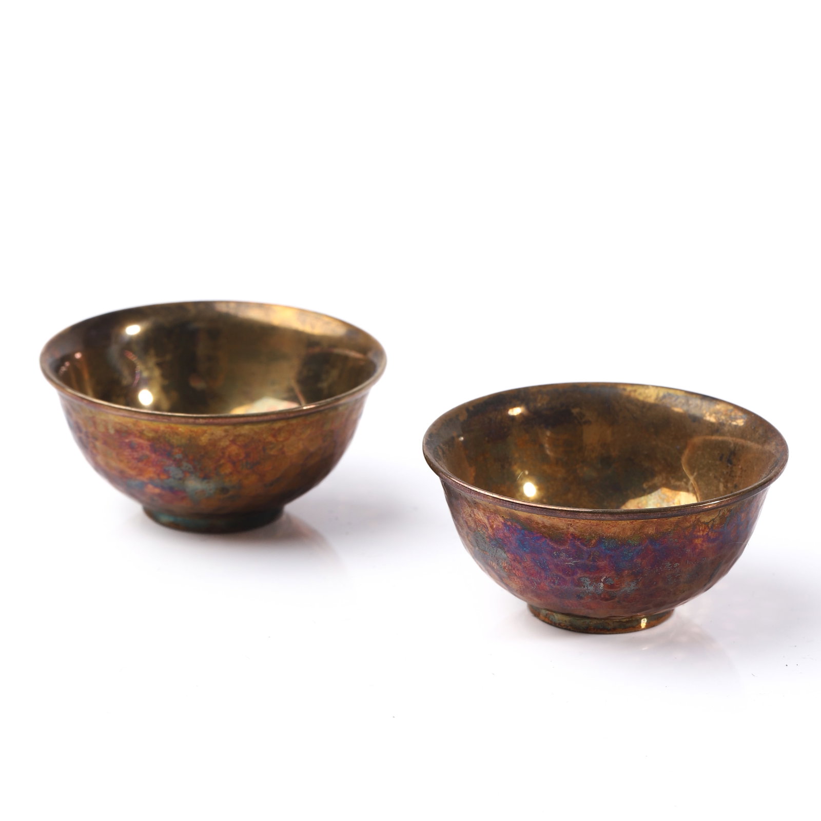 A PAIR OF SILVER-GILT BOWLS: Dimensions Diameter: 2 in (5.1 cm); Height: 15/16 in (2.4 cm); Combined Weight: 54.1g Description A pair of small gilt bowls with a hand-hammered exterior surface exhibiting multicolored heat patinati