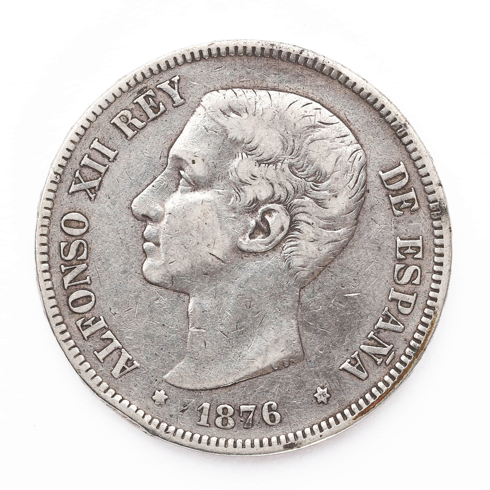 A SPANISH SILVER 5 PESETAS COIN, ALFONSO XII, DATED 1876: Dimensions: Diameter approx. 37 mm; Weight approx. 27.4 g Description: A Spanish 5 pesetas silver coin featuring a left-facing portrait of King Alfonso XII, encircled by the legend "ALFONSO XII REY DE