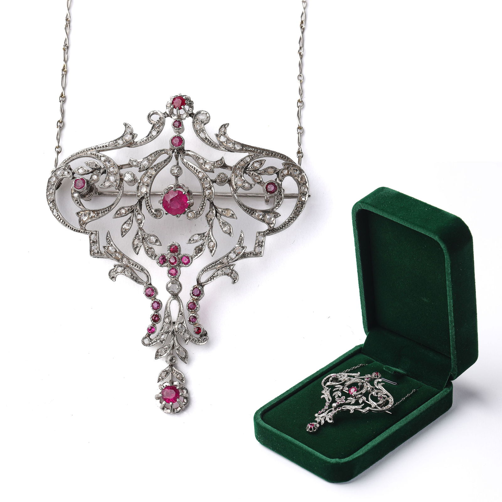 EDWARDIAN FRENCH PLATINUM, DIAMOND, AND RUBY BROOCH NECKLACE: This exquisite Edwardian-era (1901-1910) platinum brooch necklace, custom-made for French nobility, showcases the period’s signature openwork filigree with delicate milgrain detailing. Designed in a