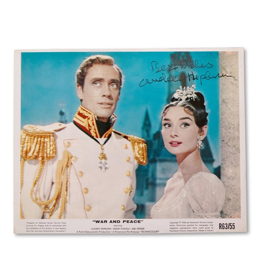 AUDREY HEPBURN SIGNED WAR AND PEACE PUBLICITY STILL (1956, PARAMOUNT PICTURES): 30 1/4 x 21 1/4 in (77 x 54 cm) This is an publicity still from Paramount Pictures' 1956 epic War and Peace, featuring Audrey Hepburn and Henry Fonda, signed in black ink by Audrey Hepburn with the in