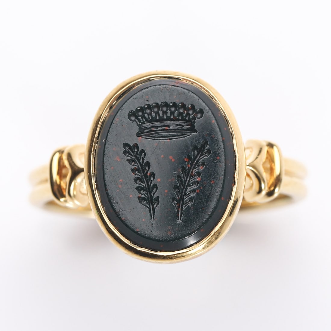 A GOLD RING SET WITH AN ENGRAVED BLOODSTONE INTAGLIO: Dimensions Inner diameter 11/16 in (16.6 mm); bezel 7/16 × 3/8 in (11.5 × 9.5 mm); weight 4 g. Description The ring mounted in yellow gold, set with an oval bloodstone intaglio finely engraved with 