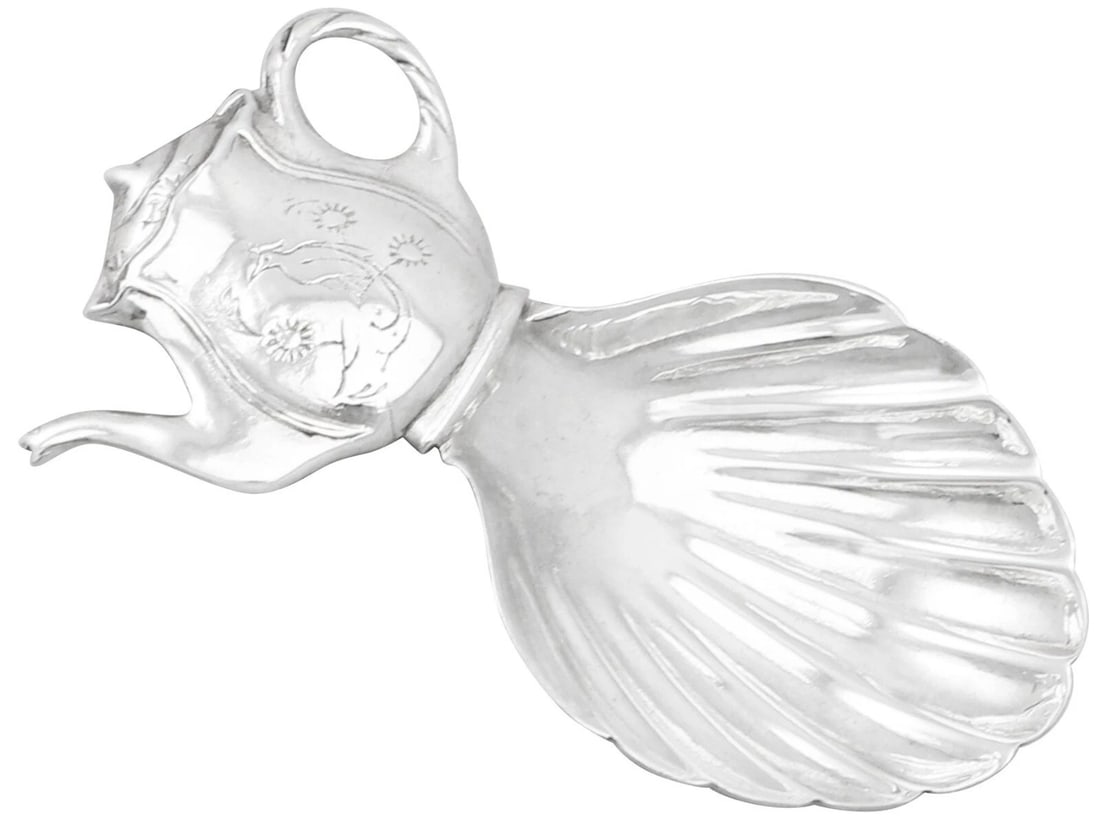SILVER-STYLE FIGURAL SHELL-FORM CREAMER: SILVER-STYLE FIGURAL SHELL-FORM CREAMER Description: A whimsical silver-tone creamer modeled with a shell-like or marine-inspired body, an elongated figural spout, and a decorative scroll handle.