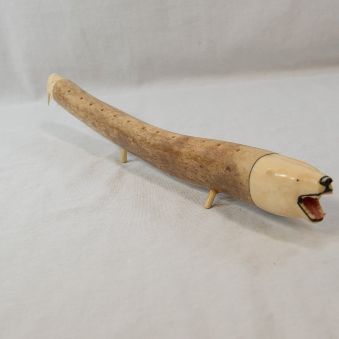 Intuit Walrus Oosik Baculum, 15.5": This walrus Oosik Baculum measures 15.5" long. It is carved on both ends - one end is carved with a walrus face, and the other shows a bear with its mouth open bearing its teeth. There are 2 rows of 1