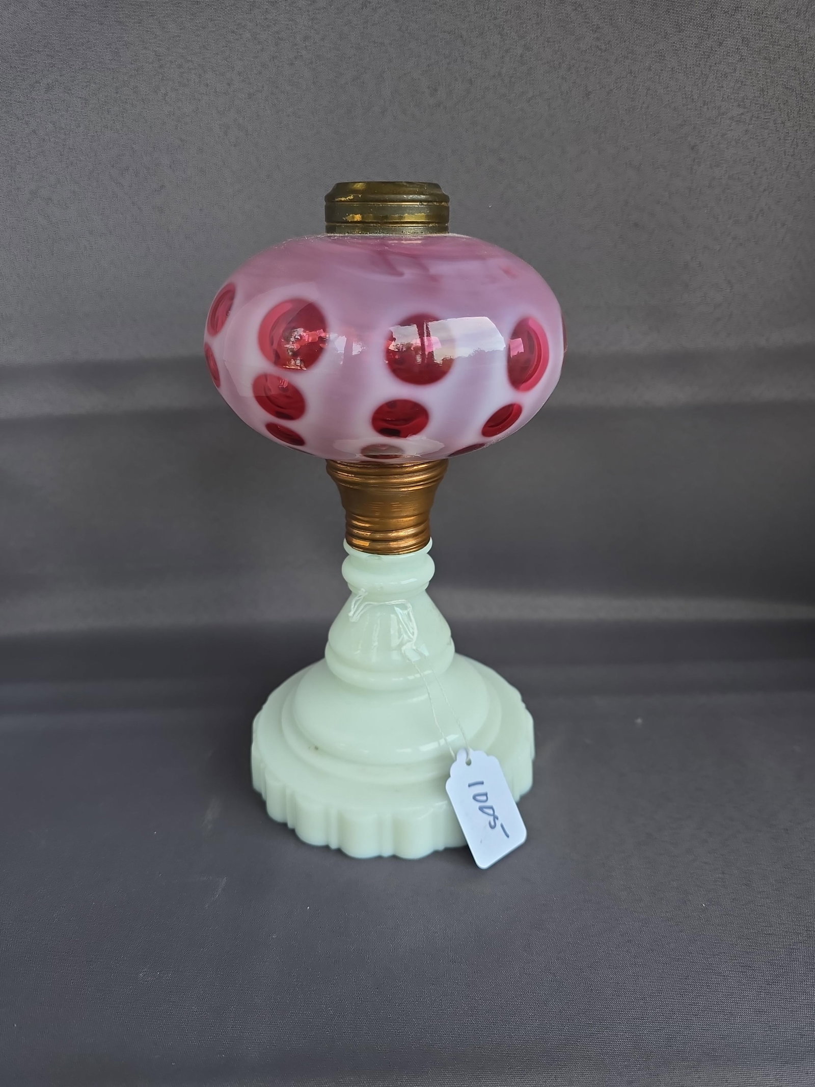 Cranberry coinspot table lamp: Cranberry top and white base 1890s 12" x 4" Low Estimate: 75.00 High Estimate: 200.00