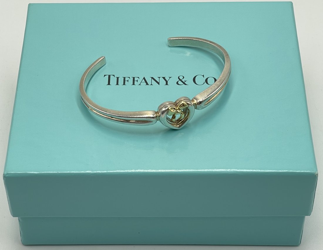 Tiffany & Co. 18K & Sterling Ribbon Bow Heart Cuff Bracelet: Tiffany & Co. Heart Bow Bangle Bracelet, a timeless piece that combines elegance and sophistication. Crafted with precision and attention to detail, this bracelet is made from high-quality sterling si