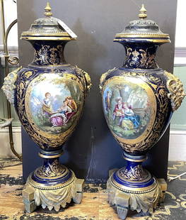 Large Pair of Sevres Bronze Mounted Cobalt Urns: Hand painted courtship scenes on cobalt blue urns. No chips or cracks, some gold loss throughout. Measure 36" tall, 17" wide.