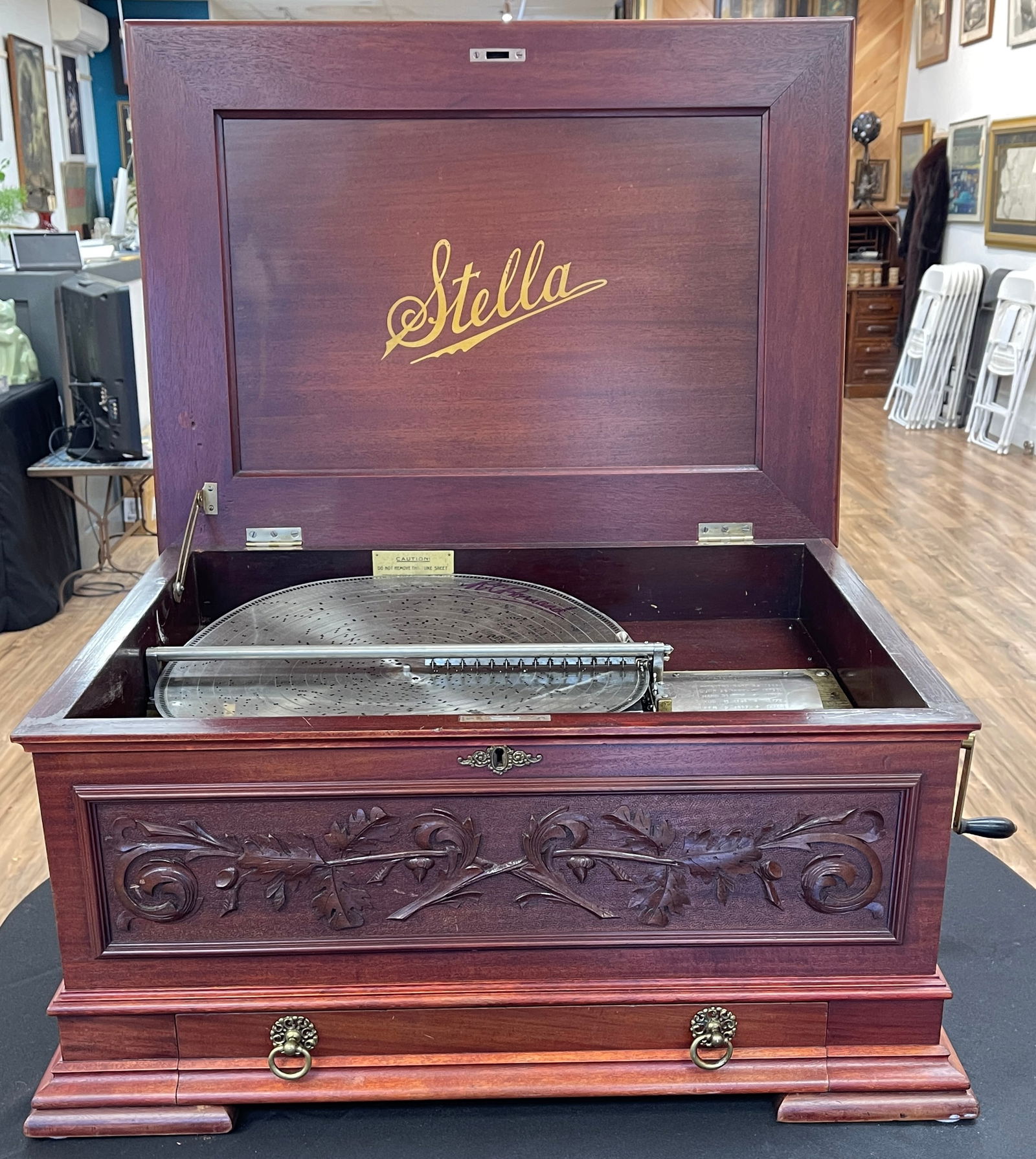 Stella Mahogany Music Box: Single comb. Swiss made mechanism. The hinged lid opens to interior windup works. Accompanied by 20 discs, each 17" in diam. Box measures 14 inches high, 29 inches wide, 20.5 inches deep. Refinished,