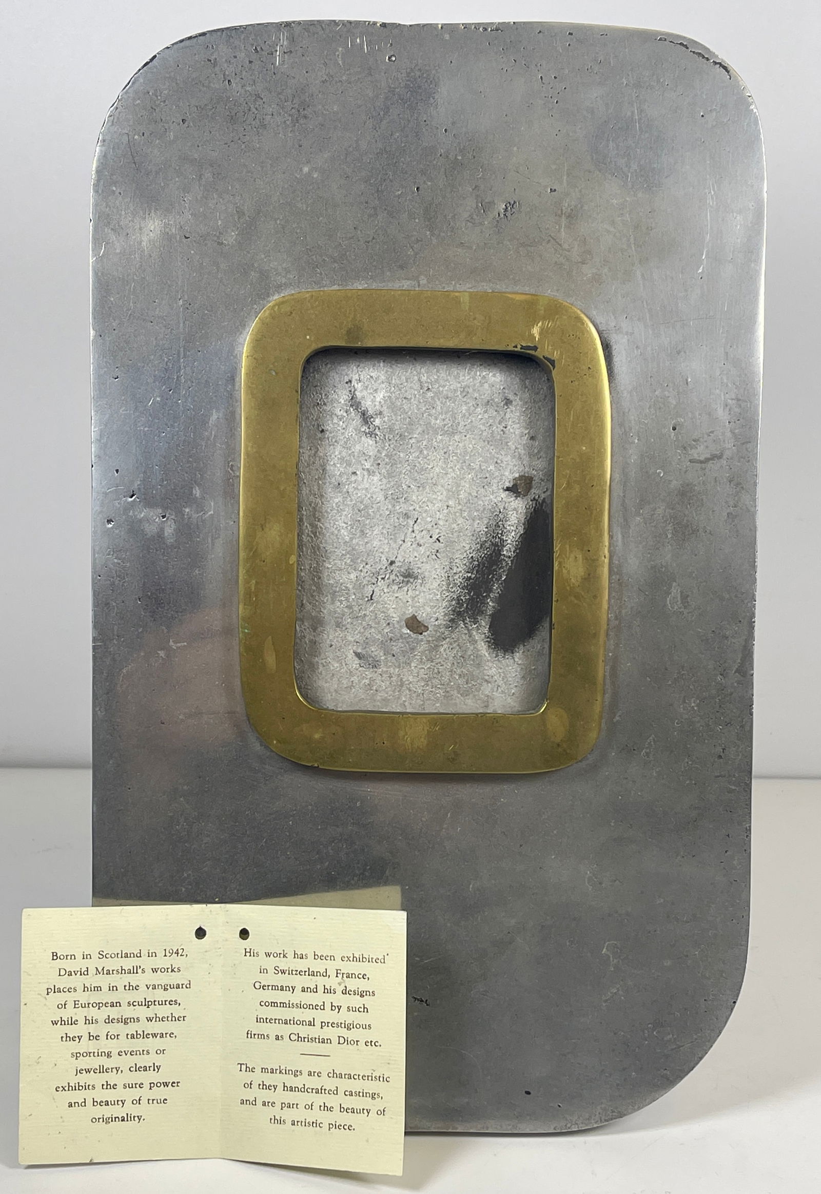 David Marshall Mixed Metal Photo Frame: David Marshall mixed metal picture frame. Composed of aluminum foundations and a brass lining enveloping the photograph. Comes with original paper tag. 11.5 in high, 7 in wide, holds a 2.75 x 3.75 in