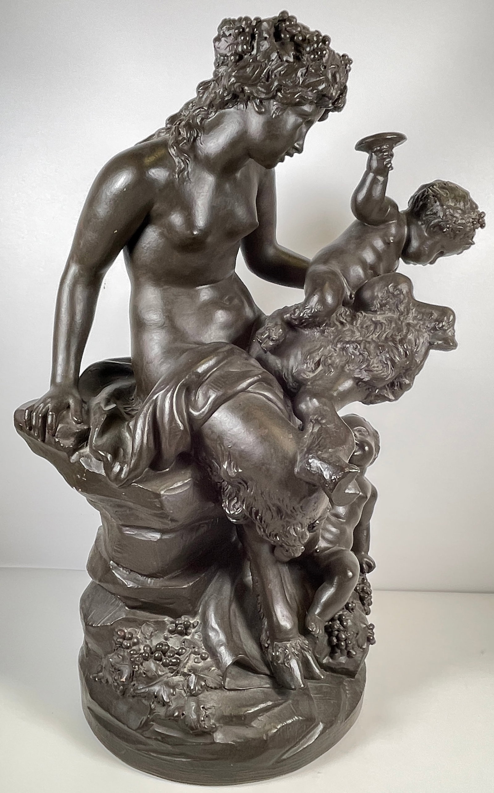 19th Century Michel Clodion Terracotta Grouping Faun & Putti: This exquisite Rococo style sculpture depicts a moment of revelry, showing a woman with two infants. She is shown holding one of them on her lap, and with another below. The naturalistic circular base