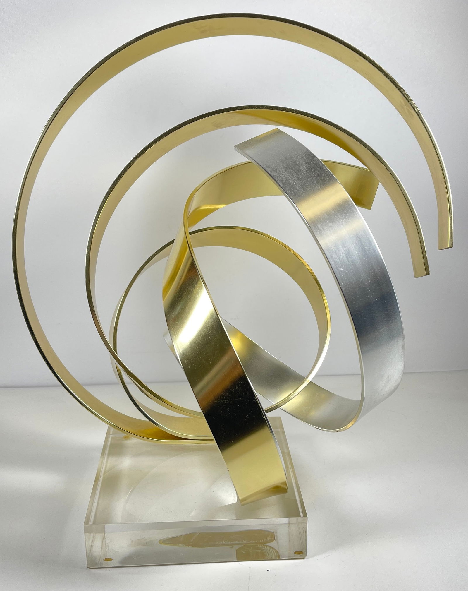 1986 Dan Murphy Modern Abstract Two Tone Ribbon Sculpture: Dan Murphy Modern Abstract Ribbon Sculpture. Two tone aluminum form. Signed and dated 1986. Measures 15.5 inches high, 15 inches wide, 12 inches deep. Set on lucite base.