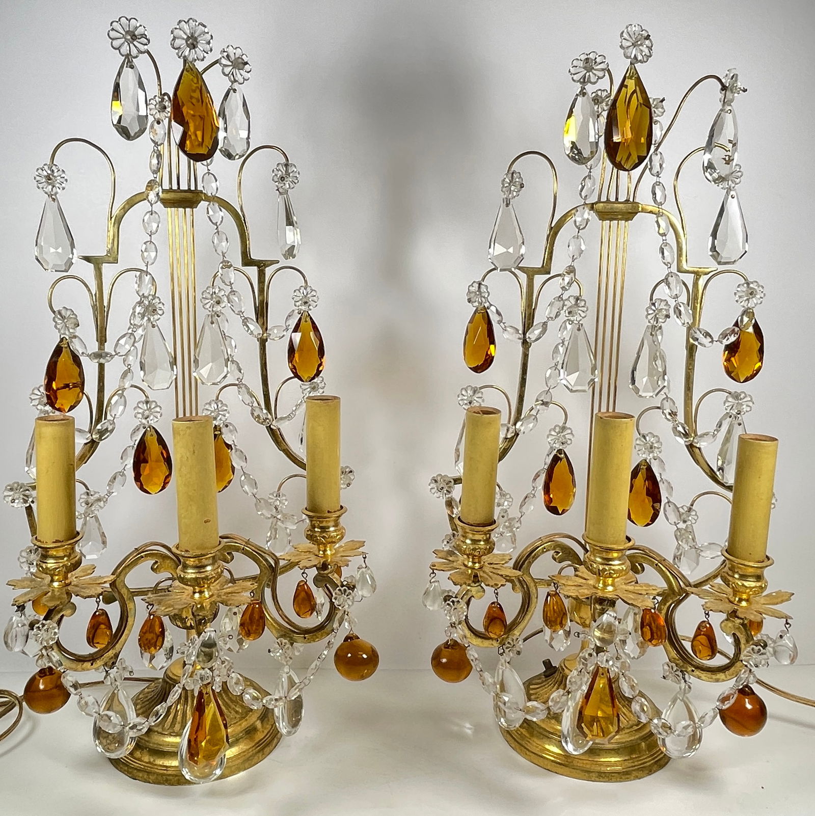 Pair French Gilt Bronze & Crystal Electrified Girandoles: Pair of gilt bronze and crystal electrified candelabra, early 20th century, having multiple tiers of foliate and teardrop accents in amber and clear crystal, leading to three electrified candles surmo