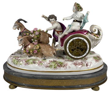 c1900 Meissen Style Porcelain Figural Mantel Clock: Depicting a boy and girl, possibly Apollo and Artemis, in a chariot led by two goats, mounted on marble base. Overall good condition, one goat has a repaired horn, some chips to the head of one figure