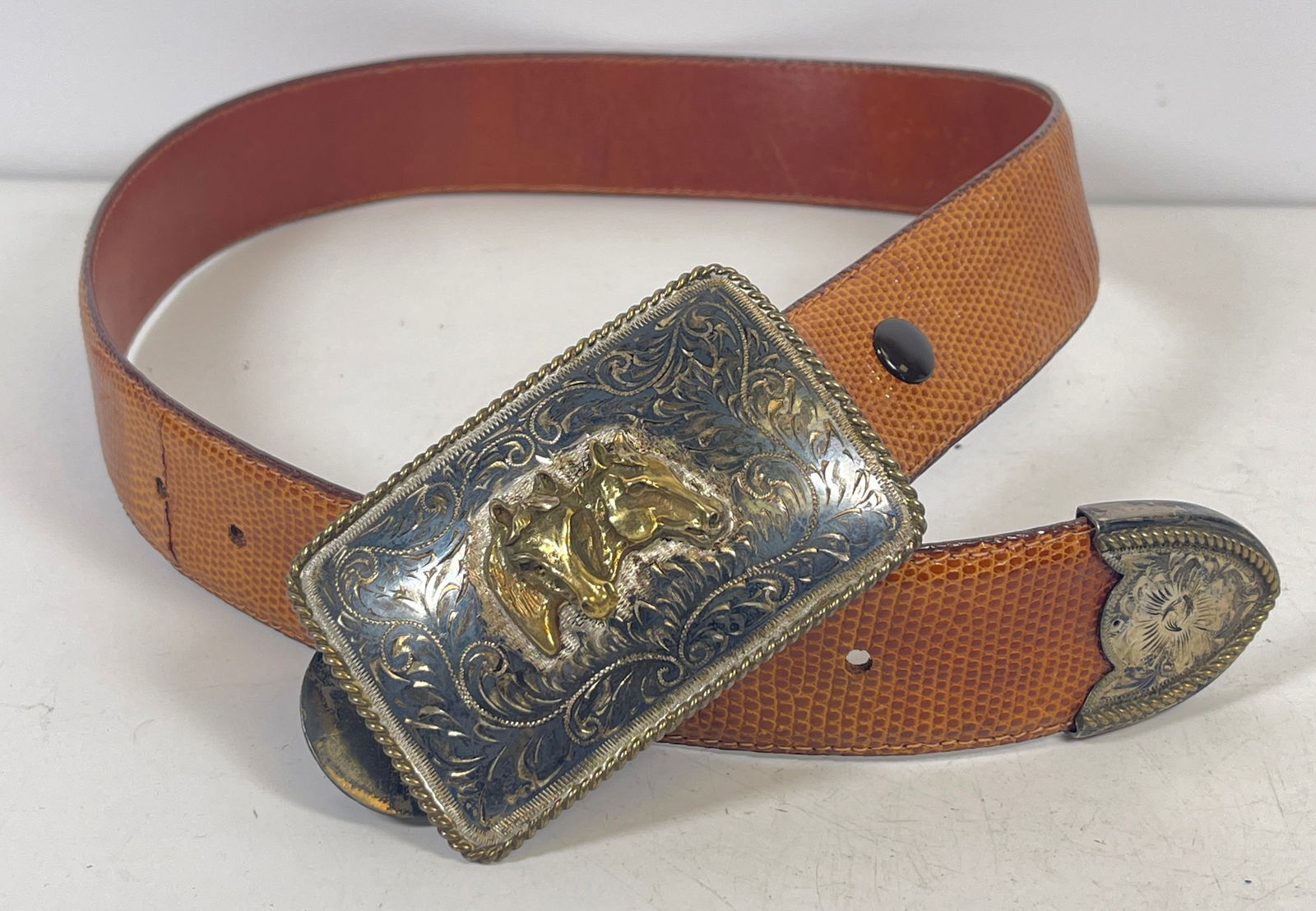 Vintage Ralph Lauren Polo Sterling Overlay Buckle & Leather Belt: Leather belt featuring a Polo sterling with overlay buckle by Ralph Lauren decorated with horse designs and braided border. Belt measures 31 inches long, 1.5 inches wide. Buckle measures 3.5 inches lo