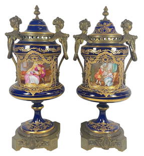 Pair 19C Sevres Bronze Mounted Cobalt Porcelain Urns: Cobalt blue ground, with figural handles. Courtship scene on one side, landscape scene on the other. Measures approx 18.5 inches high, 7.5 inches handle to handle. Marked on the bottom. Overall good c