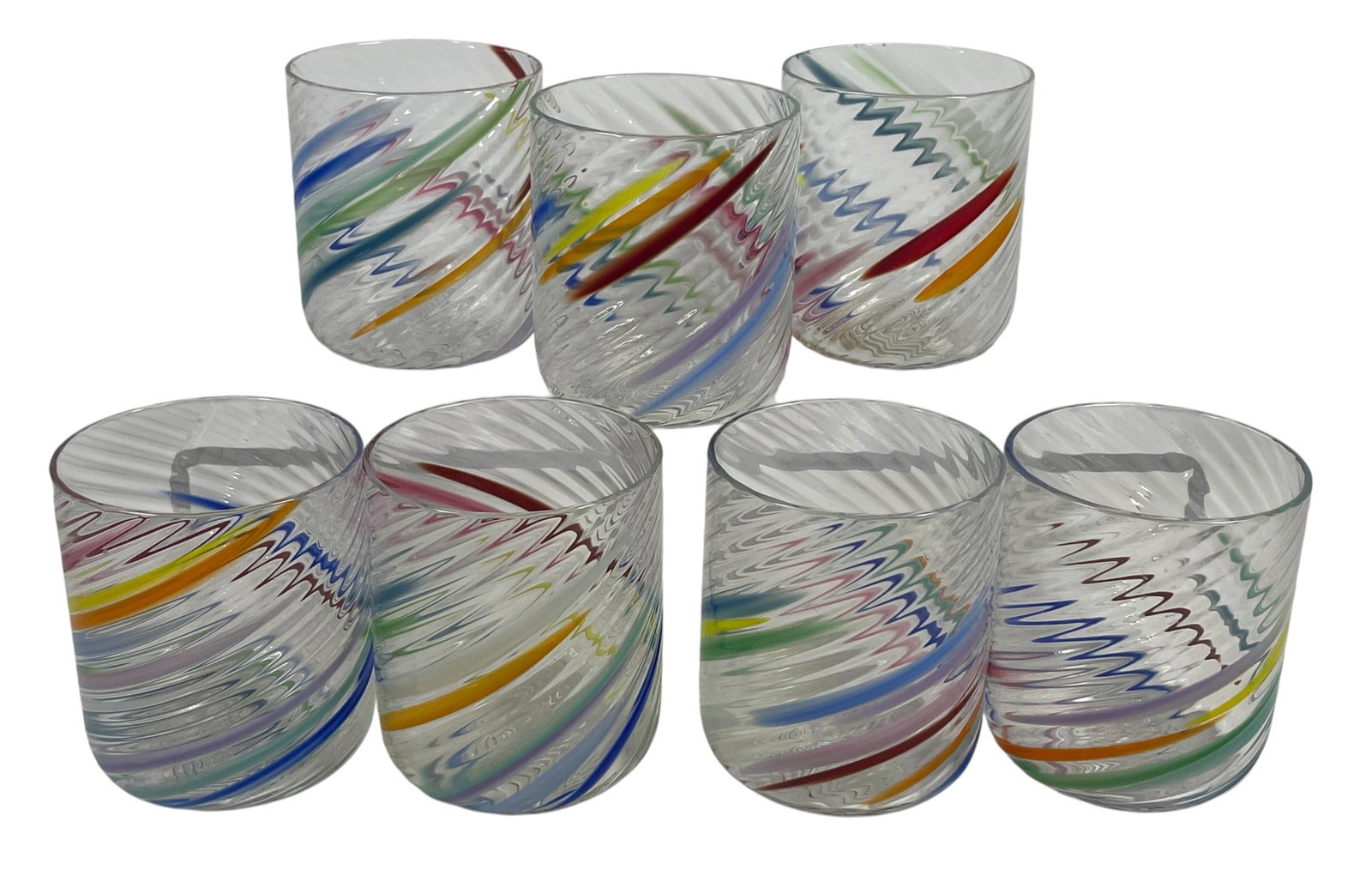 (7) Attb Tom Stoenner Art Glass Rocks Glasses: Swirls of colorful canework combine with bold grooves to create striking optical effects in these blown glass rocks glasses. Has a signature across the bottoms, can only make out "Glass 1987" There is