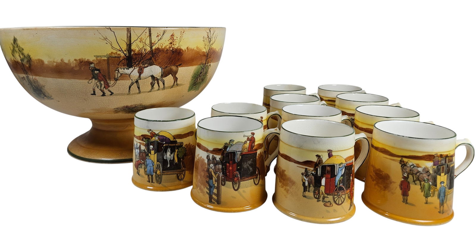 c1920 Royal Doulton Seriesware 'Coaching Days' Punch Bowl and Mugs: To include (1) large footed punch bowl and (11) mugs, featuring hand painted coaching scenes. Royal Doulton backstamp. Bowl measures 7 inches high, 12.25 inches wide across the top, mugs measure 3