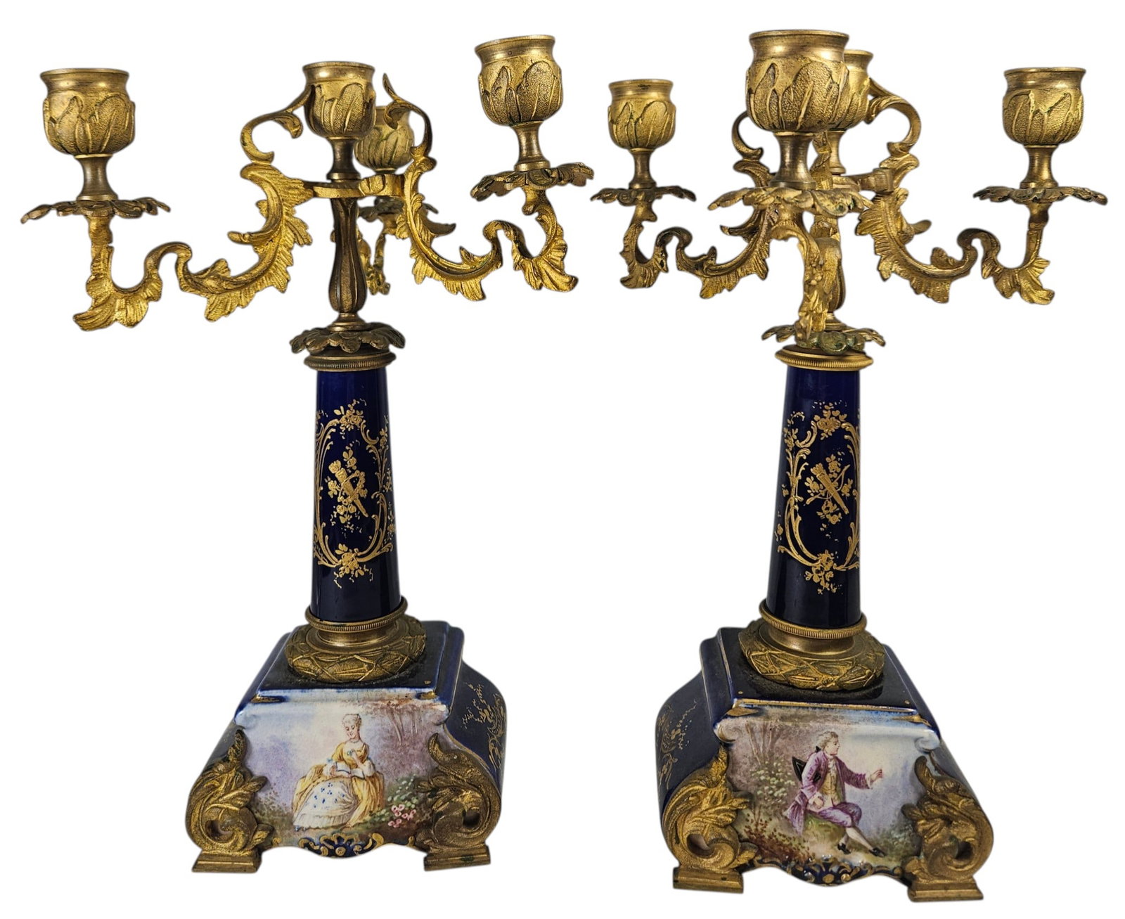 Pair 19th Century French Sevres Cobalt Blue Porcelain & Bronze Candelabras: Central column and base made of cobalt blue porcelain, hand decorated with gilt floral and figural motifs. Mounted with ornate scrooling gilt bronze elements including three foliate arms. Measures 11.